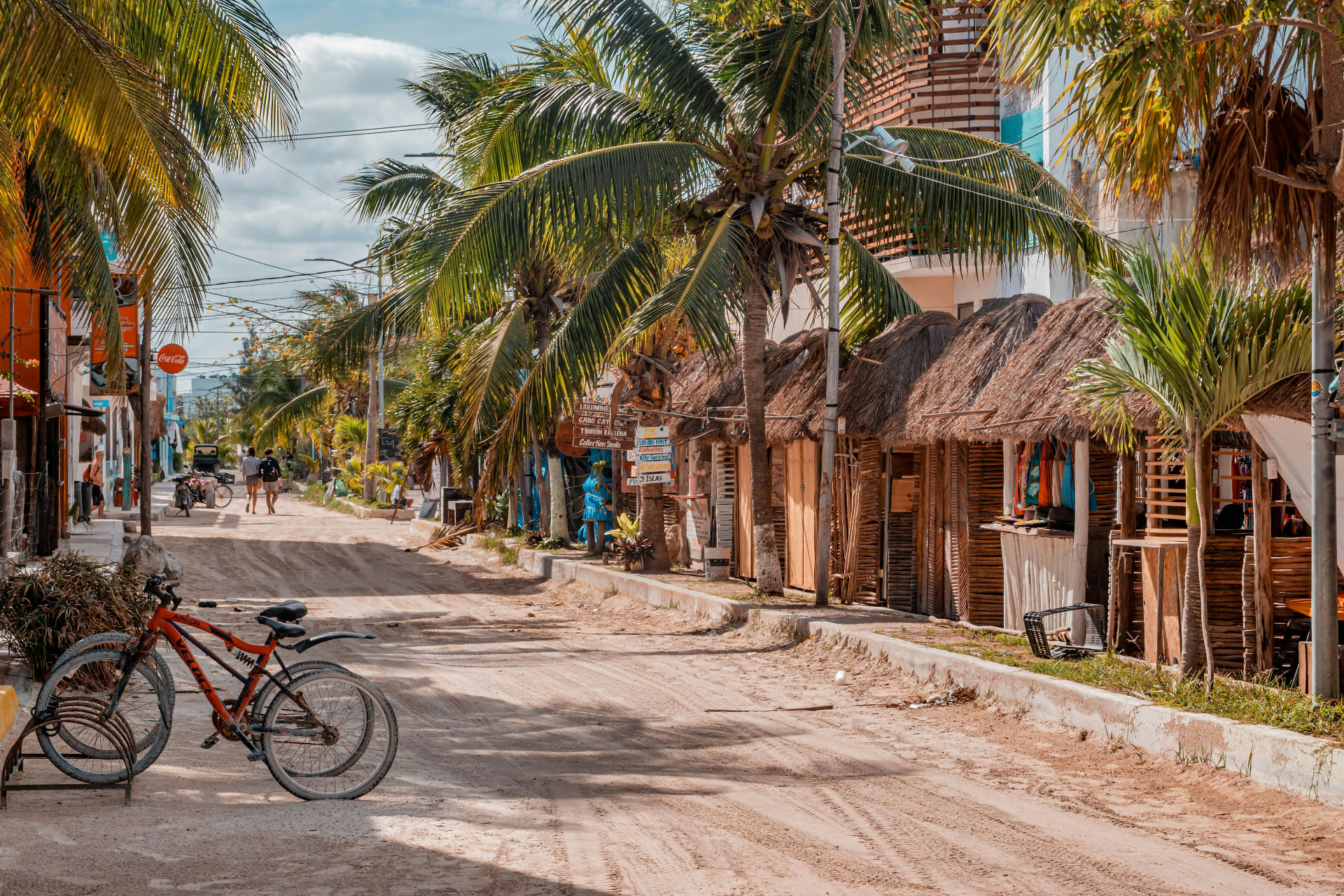 Calle de arena con palmeras y bicicletas en la isla de Holbox, México